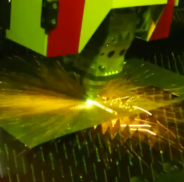 Urządzenie przemysłowe z zielono-czerwonymi elementami wykonujące cięcie laserowe metalu. Widoczny jasny żółty snop światła l