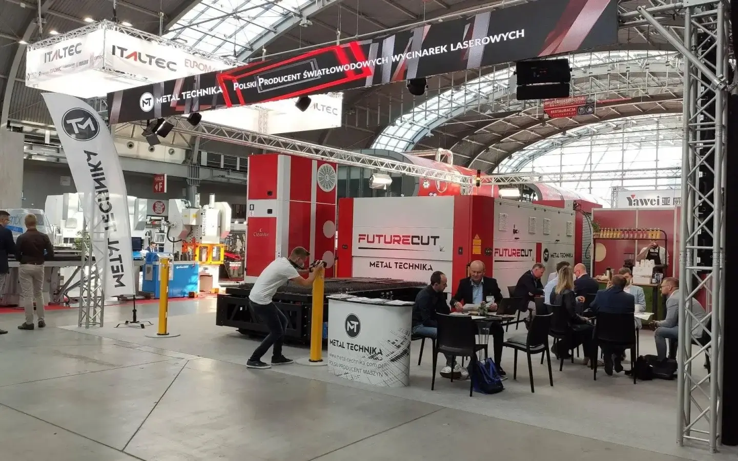 Stoisko wystawiennicze Metal Technika z urządzeniami Futurecut na targach w hali wystawowej. Czerwone maszyny do cięcia laser